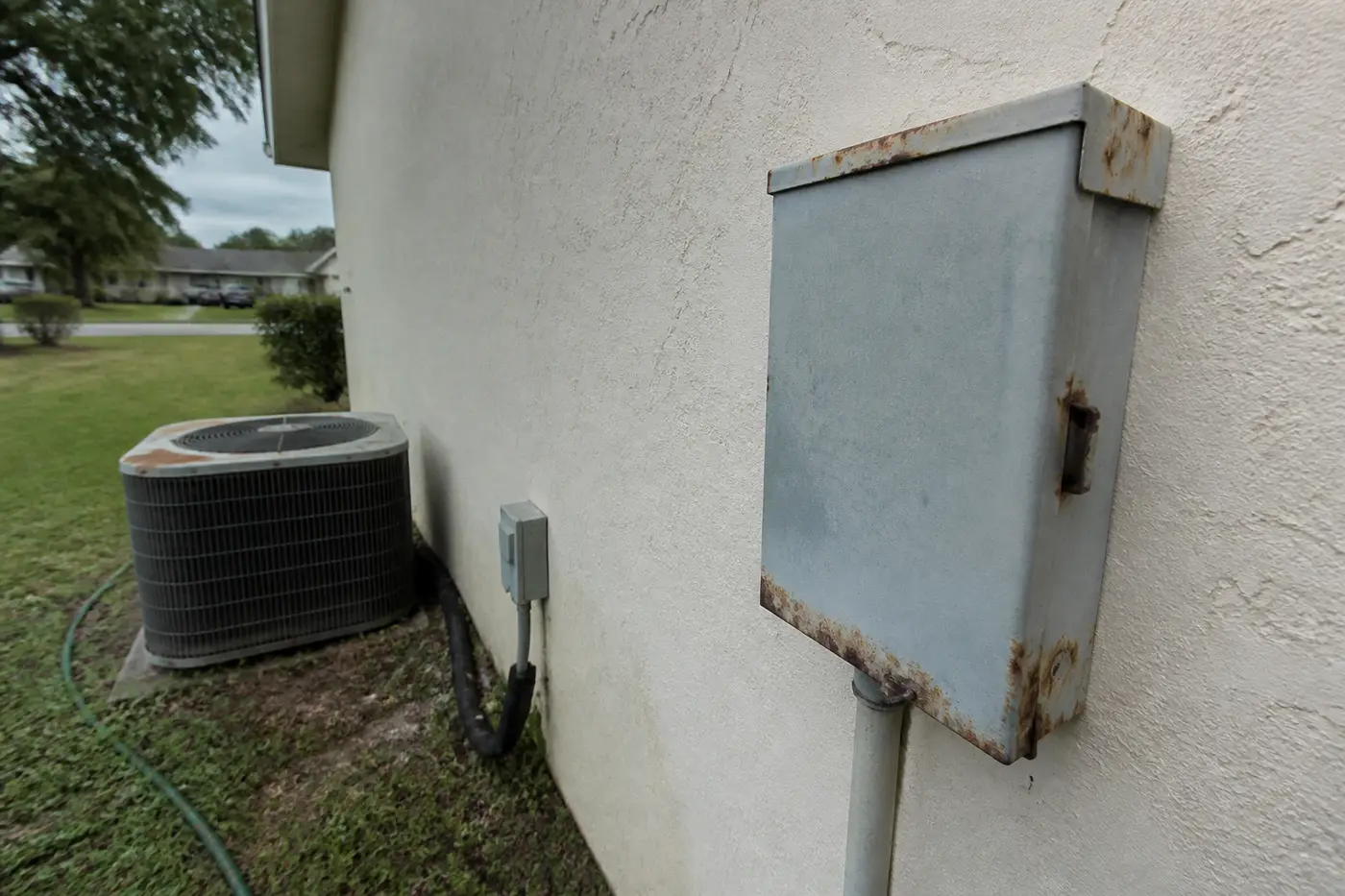 How long an AC lasts in Florida: rusted outdoor disconnect Rusty AC disconnect beside an old condenser, typical wear after 15 years in Florida