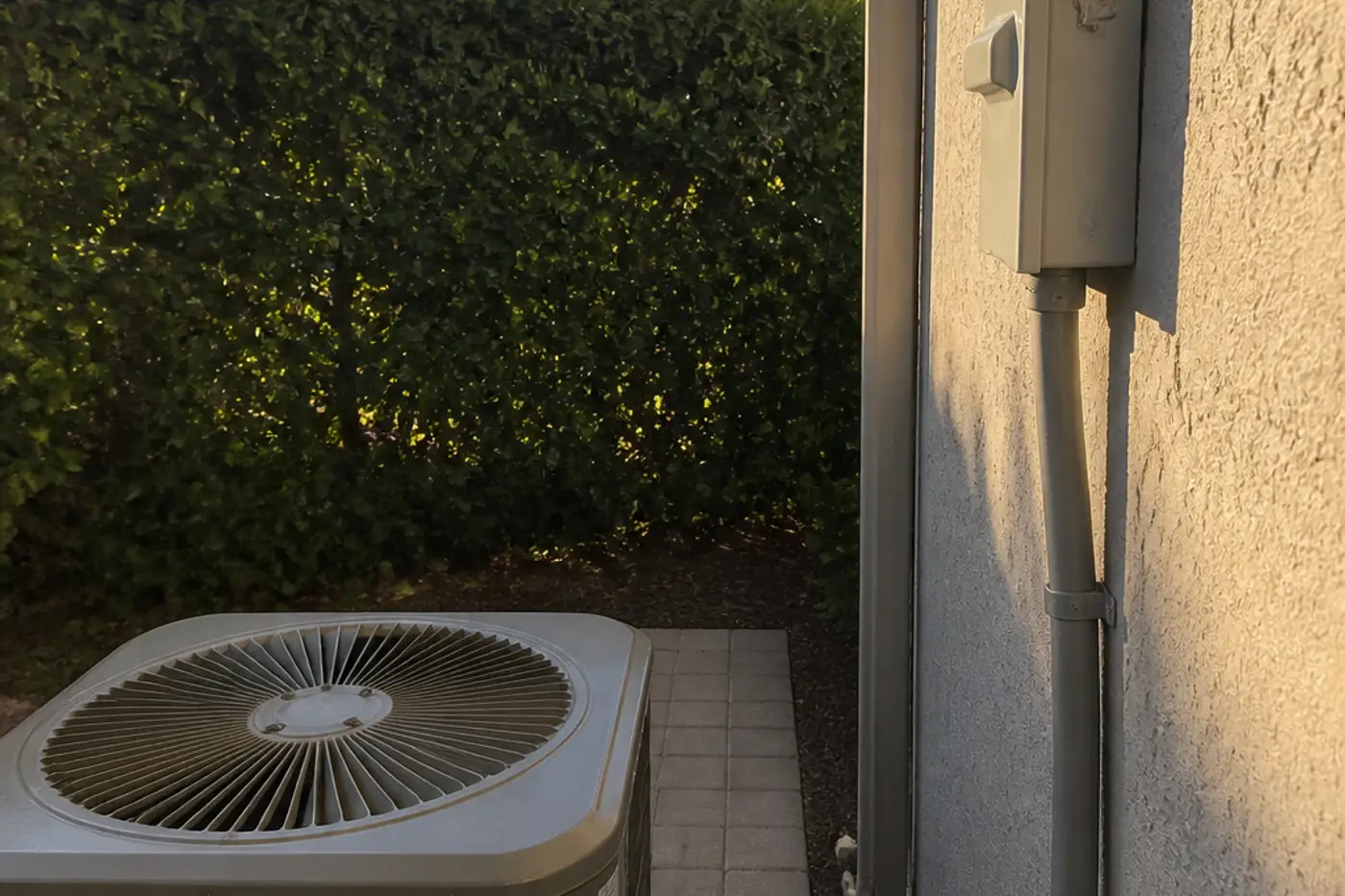 Outdoor AC disconnect and whip on a Lutz stucco wall next to the condenser
